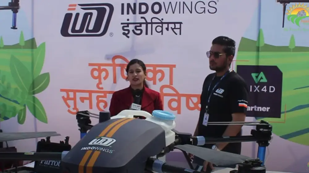 a man stands in black waist coat and white shirt in front of the drone which black and white colour